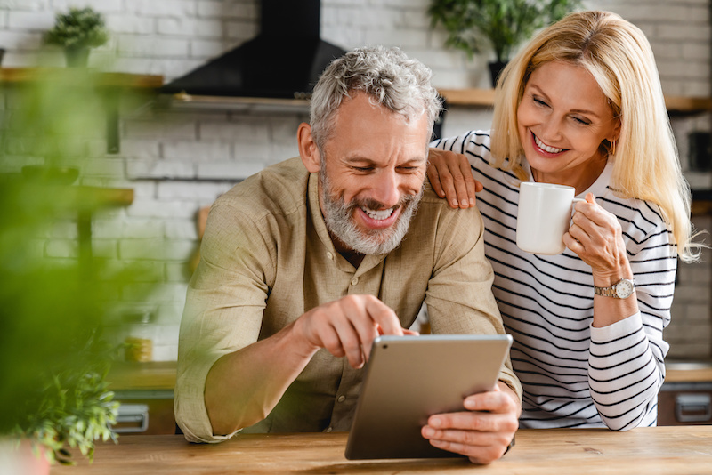 Happy senior couple using digital tablet in kitchen at home